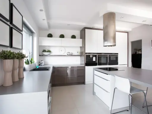 Cocina moderna con isla central y campana extractora cilíndrica. Es obligatorio tener campana extractora en la cocina para mantener el aire limpio.