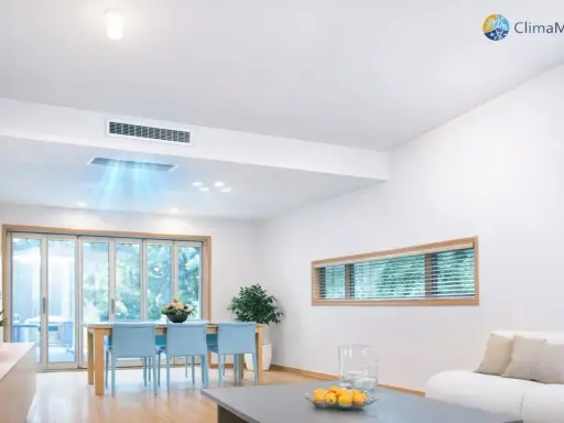 Instalación de aire acondicionado por conductos en un salón moderno. El sistema distribuye aire fresco de forma discreta.