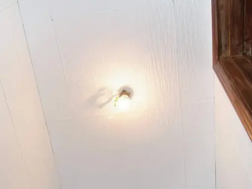 Techo con paneles de poliestireno extruido, una bombilla encendida y un marco de madera.