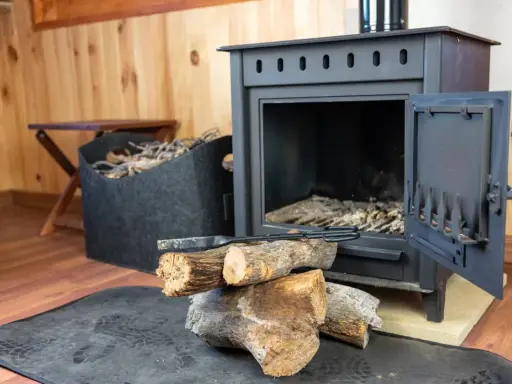Estufa de hierro con leña y herramientas. Aprende como limpiar chimenea de hierro por fuera para mantenerla impecable.