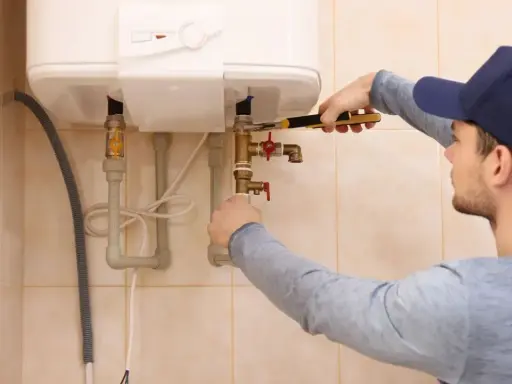 Un técnico ajusta las tuberías de un calentador de agua. Espera que la luz del termo no se apaga para confirmar que todo funciona bien.