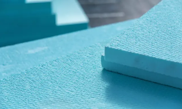 Planchas de poliestireno extruido (XPS) de color azul, apiladas y listas para aislamiento. El XPS es un material ligero y resistente.