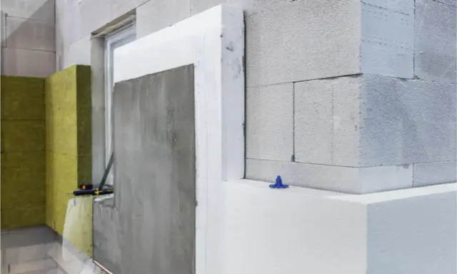 Detalles de construcción: ejemplos de aislantes térmicos como poliestireno y lana mineral en una pared de bloques.