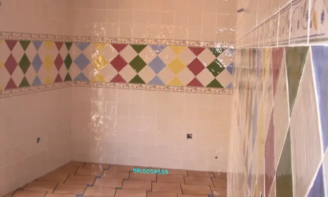 Detalle de azulejos en una pared, mostrando la diferencia entre mortero capa fina y capa gruesa en un diseño de rombos.