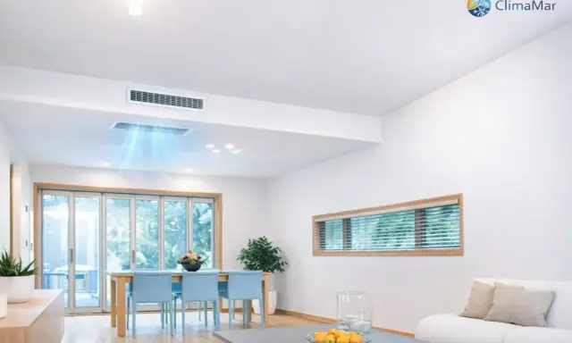 Instalación de aire acondicionado por conductos en un salón moderno. El sistema distribuye aire fresco de forma discreta.