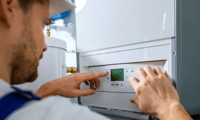 Técnico ajustando un calentador de gas butano. El esquema de instalación es complejo, pero él lo domina.