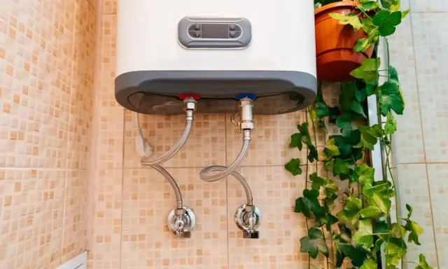 Termo eléctrico no sale agua caliente. Las tuberías de conexión y las válvulas están visibles en la pared con azulejos.