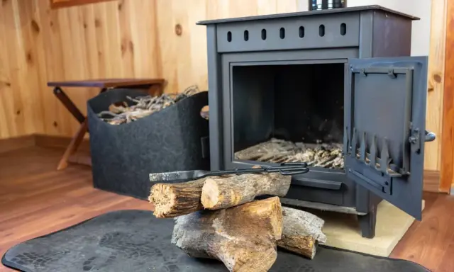 Estufa de hierro con leña y herramientas. Aprende como limpiar chimenea de hierro por fuera para mantenerla impecable.