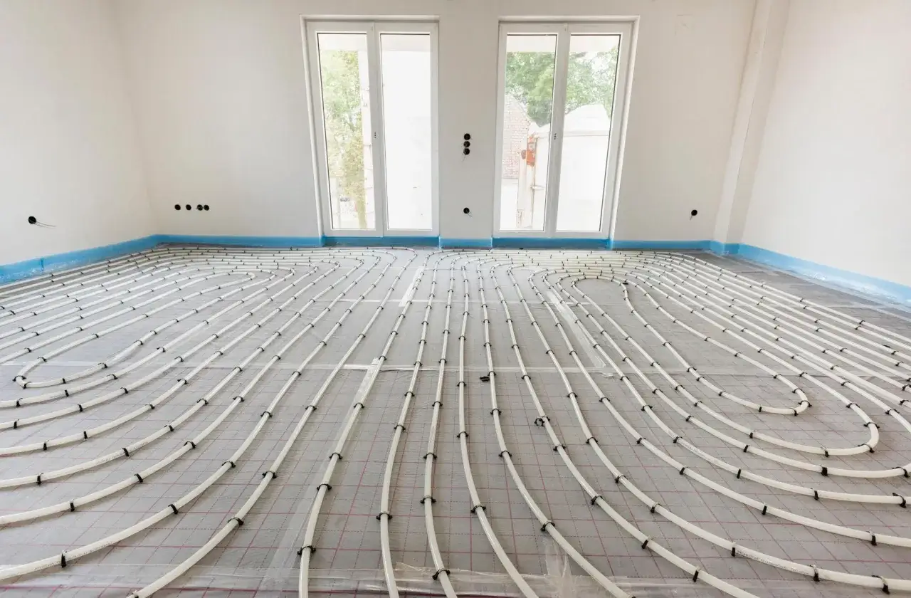 Instalaci&oacute;n de tuber&iacute;as para el suelo radiante enfria, cubriendo el suelo de una habitaci&oacute;n en construcci&oacute;n con grandes ventanales.
