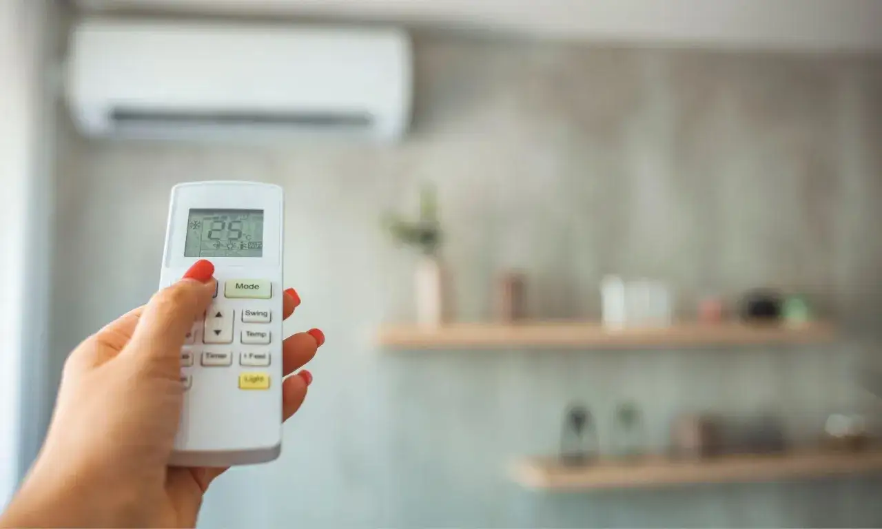 Mano ajustando la temperatura de consigna del aire acondicionado a 28&deg;C con el mando a distancia.
