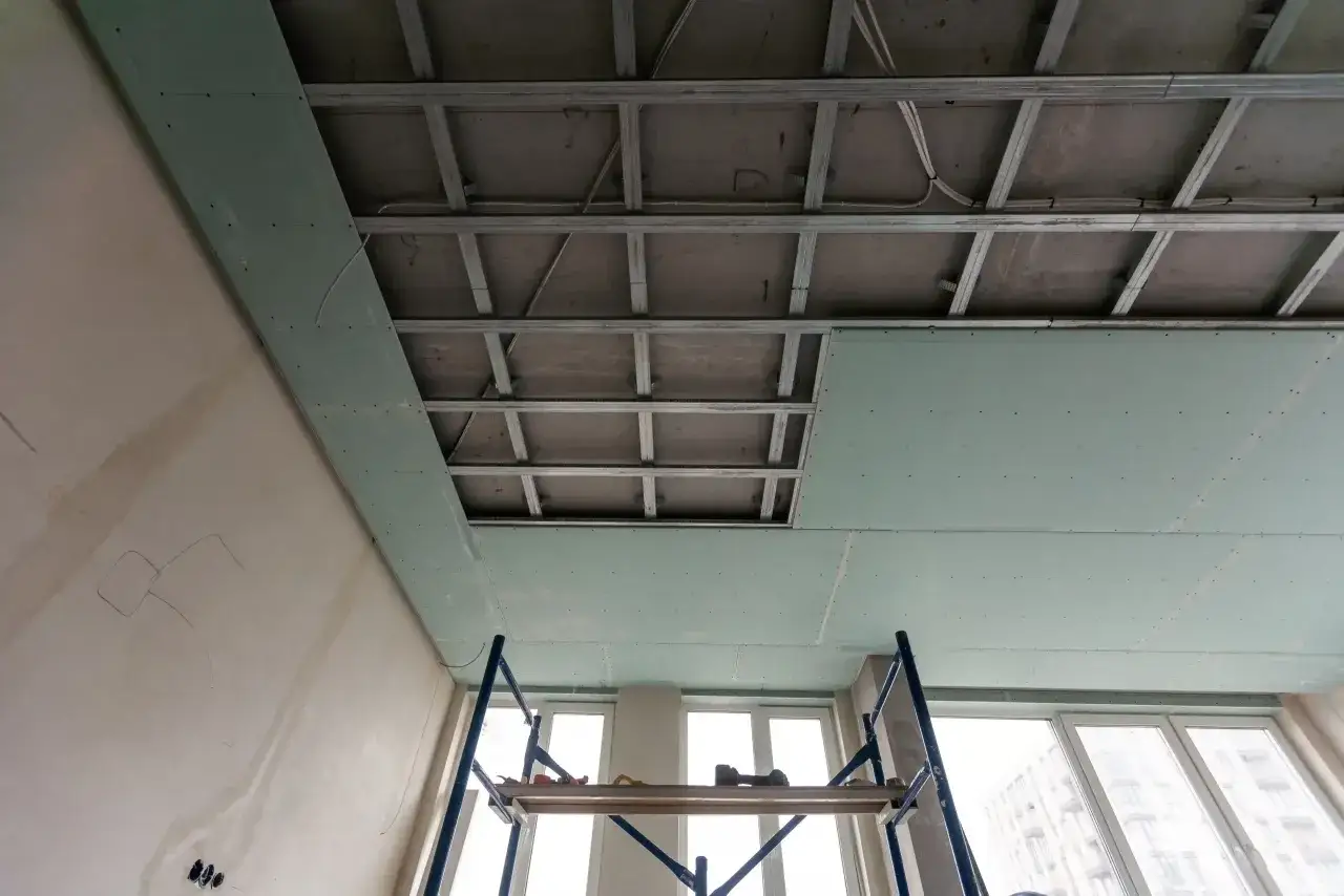 Instalaci&oacute;n de falso techo de pladur para aislar techo ruido vecinos. Estructura met&aacute;lica y placas verdes visibles.