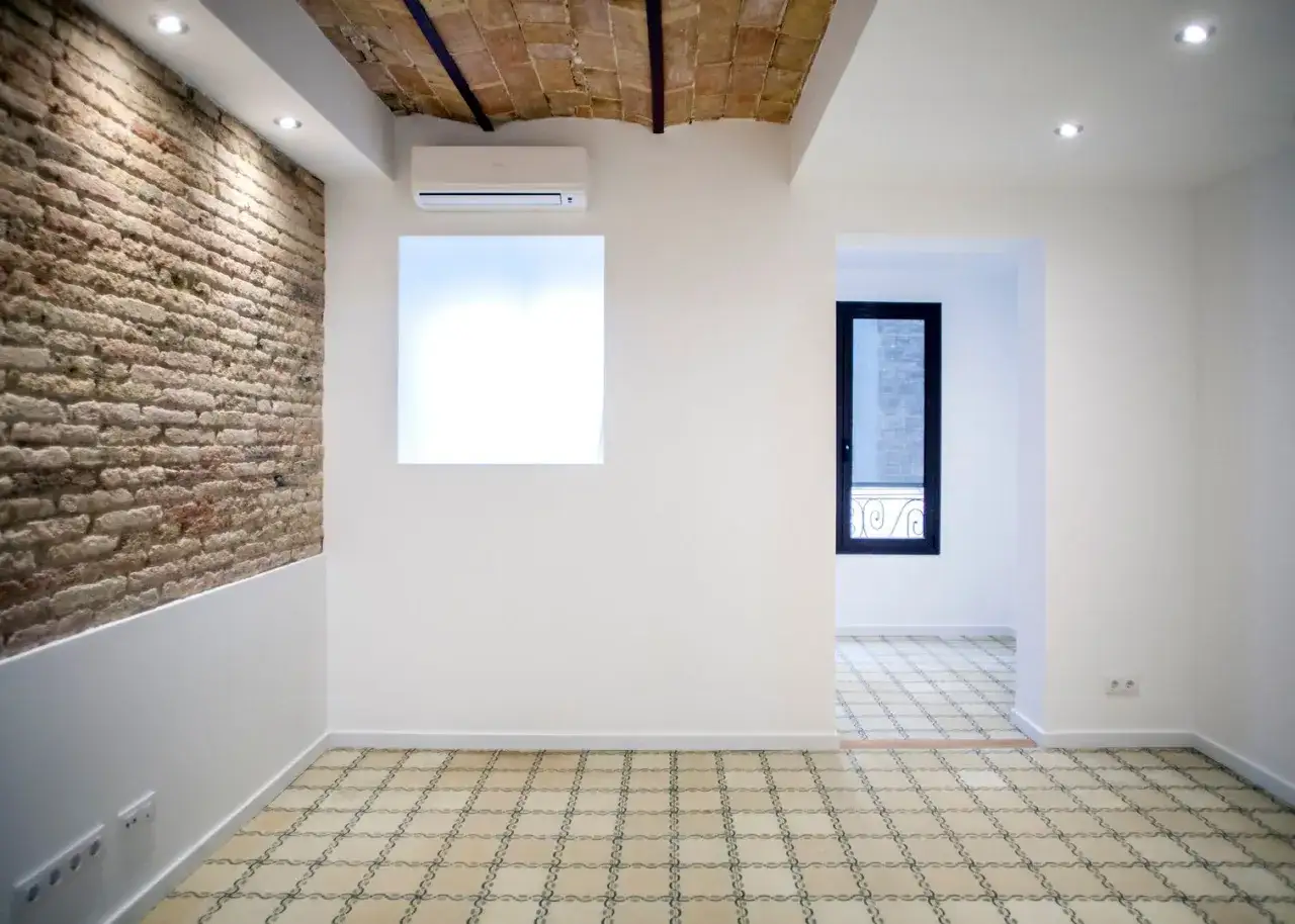 Interior moderno con pared de ladrillo visto y suelo hidr&aacute;ulico. Se ha decidido tirar tabique para unir dos pisos, creando un espacio di&aacute;fano.