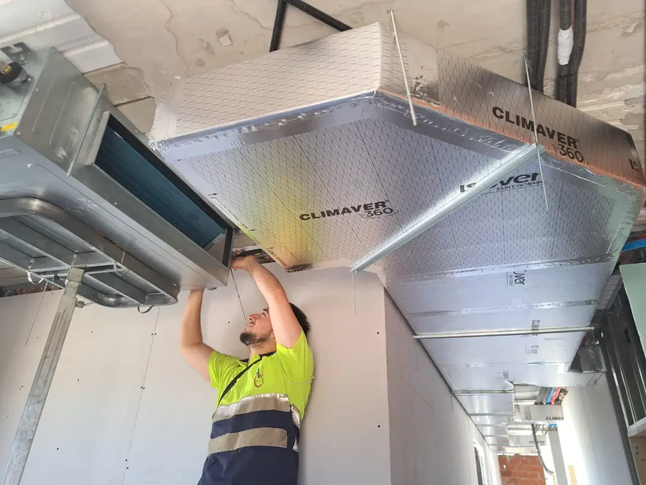 Técnico instalando sistema de climatización central, proceso de poner aire acondicionado por conductos.