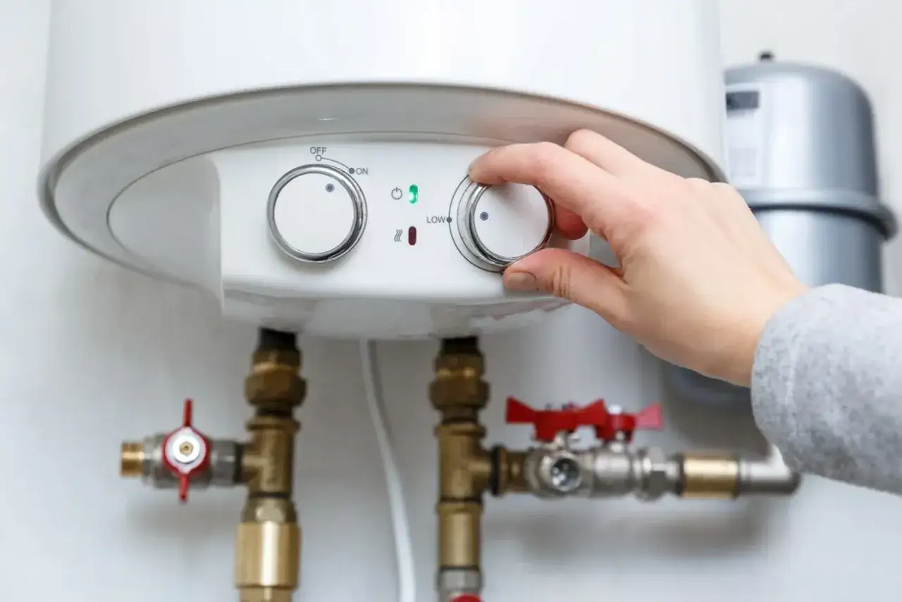Mano ajusta el control del termo eléctrico. El piloto no enciende, indicando un posible problema.