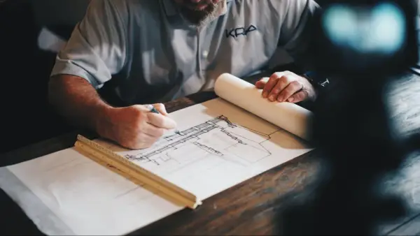 Arquitecto dibuja planos detallados, calculando la superficie edificable para un nuevo proyecto.