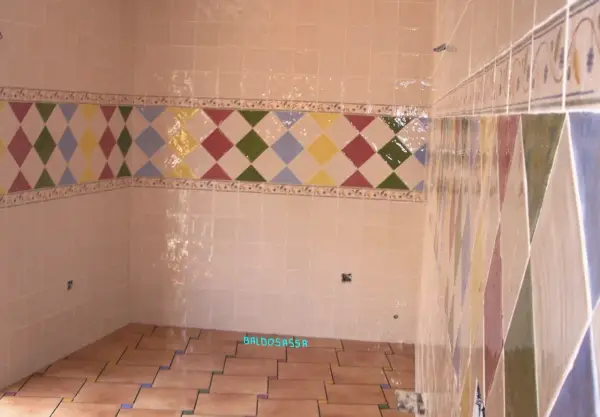 Detalle de azulejos en una pared, mostrando la diferencia entre mortero capa fina y capa gruesa en un diseño de rombos.