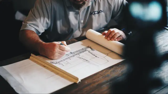 Arquitecto dibuja planos detallados, calculando la superficie edificable para un nuevo proyecto.